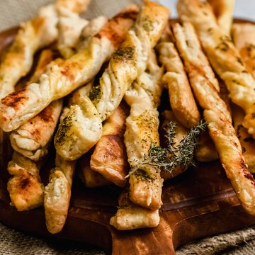 Käsestangerl auf einem Teller bestreut mit Kräutern