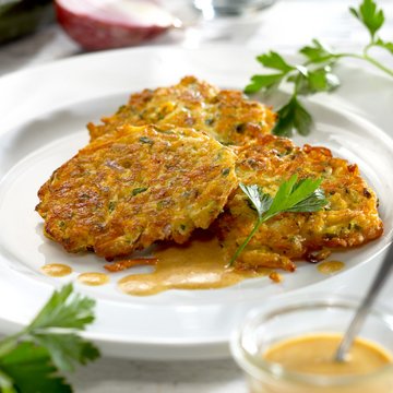 Gemüselaibchen mit Curry-Joghurt-Soße lecker auf einem Teller angerichtet und mit Petersilie verziert