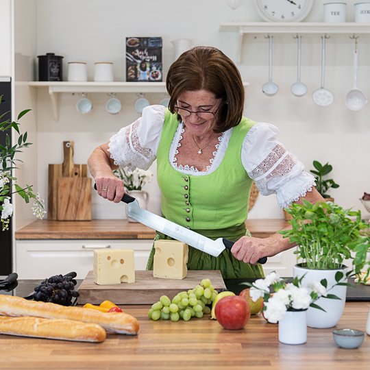 Frau schneidet Käse in der Küche